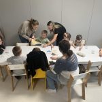 Dzieci z pomocą nauczyciela i opiekuna wlewają wodę do słoiczka z gazą.