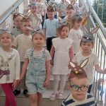 Duża grupa dzieci w czapkach zajączka stoją na schodach klatki schodowej.