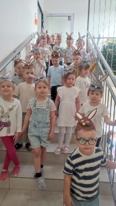 Duża grupa dzieci w czapkach zajączka stoją na schodach klatki schodowej.