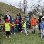 Dzieci z opienunami stoją przed zagrodą ze zwierzętami- kózki.