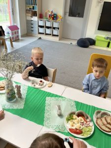 Dzieci siedzą przy stoliczku i jedzą świąteczne śniadanie.