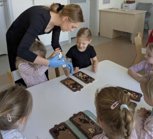 Dziewczynki nalewają czekoladę do specjalnych foremek