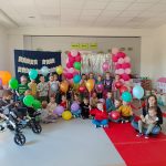 Dzieci trzymają w ręce balony z okazji Dnia Godności Osób z Niepełnosprawnościami.