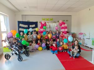 Dzieci trzymają w ręce balony z okazji Dnia Godności Osób z Niepełnosprawnościami.