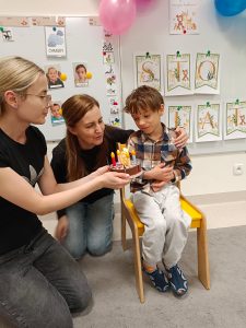 Chłopiec zdmuchuje świeczkę urodzinową na torcie.
