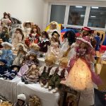 Kolekcja porcelanowych lalek ułożone na białych stołach.