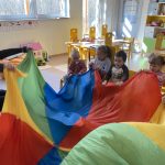 Dzieci i Panie trzymają kolorową chustę animacyjną