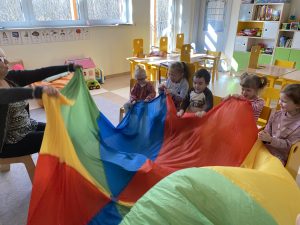 Dzieci i Panie trzymają kolorową chustę animacyjną