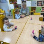 Dzieci z Panie przy stolikach W rękach trzymają ciastolinę i klocki