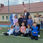 Dziesięcioro dzieci i dwie Panie znajdujący się na boisku sportowym. Dzieci maja założone medale.