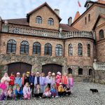 Cała grupa pozuje do zdjęcia na tle zamku