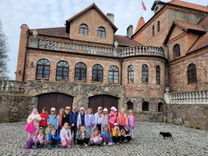 Cała grupa pozuje do zdjęcia na tle zamku