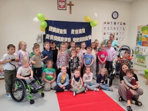 Wszystkie grupy dzieci pozują w sali do zdjęcia