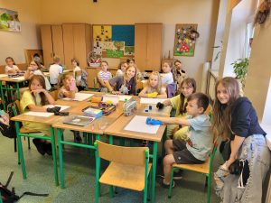 Dzieci siedzą w klasie i uczestniczą w lekcji