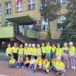 Dzieci stoją przed budynkiem szkoły i pozują do zdjęcia