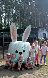 dzieci pozują do zdjęcia przy białym króliczku