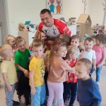 Grupa dzieci i Pan stojący w sali przedszkolnej.