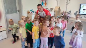 Grupa dzieci i Pan stojący w sali przedszkolnej.