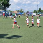 Dzieci i osoby dorosłe uczestniczący w zajęciach sportowych na boisku.