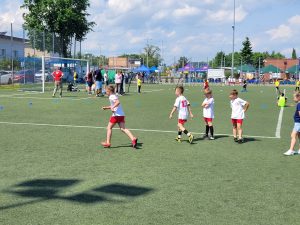 Dzieci i osoby dorosłe uczestniczący w zajęciach sportowych na boisku.