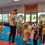 Grupa dzieci wraz ze sportowcem będąca w klubie samoobrony Respect.