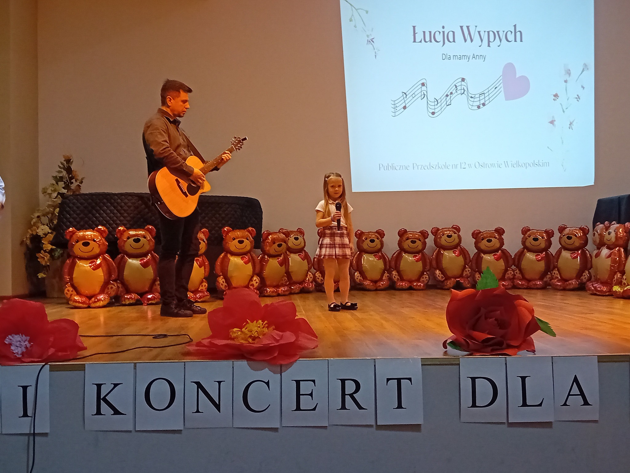 Występ na scenie dziewczynki. Towarzyszy jej tata grający na gitarze