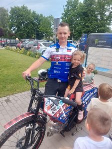 Dziewczynka siedząca na motorze, obok zaproszony gość