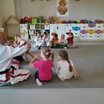 Grupa dzieci z instruktorem w białym kimono demonstrują pokazane chwyty