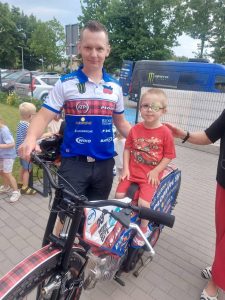 Chłopiec siedzący na motorze, obok zaproszony gość