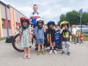 Czworo dzieci w żużlowych kaskach na głowie, razem z zaproszonym gościem.