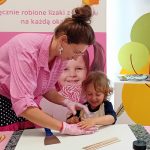 Chłopiec i pani w różowej koszuli przy stole robią lizaka