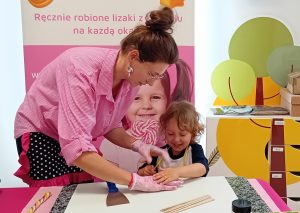 Chłopiec i pani w różowej koszuli przy stole robią lizaka
