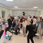 Duża grupa rodziców tańczy w parach na szarym dywanie.