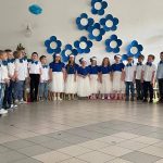 Grupa dzieci kończących przedszkole występuje na uroczystości dla swoich rodziców i zaproszonych gości. Dzieci są odświętnie ubrane, dziewczynki mają długie, tiulowe spódniczki, na głowach białe opaski z niebieskim kwiatem i modrakowe bluzeczki z krótkim rękawem. Chłopcy mają modrakowe muchy przy kołnierzykach swoich białych koszul, ciemne długie spodnie. Wszystkie dzieci wyglądają elegancko. Tańczą parami, tańczą poloneza. Tak więc para za parą. W tle dekoracje.