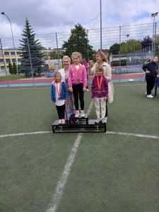 Dzieci stojące na podium podczas olimpiady sportowej. Na 2 miejscu stoi Zosia.