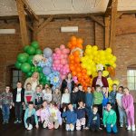 Grupa 20 dzieci w wieku przedszkolnym pozuje do zdjęcia na tle ścianki z balonów i dmuchanych zajączków na zamku w Gutowie. Na zdjęciu znajdują się również 3 panie nauczycielki grupy.