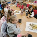 Dzieci siedzą przy stołach podczas słodkiego poczęstunku