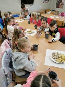 Dzieci siedzą przy stołach podczas słodkiego poczęstunku