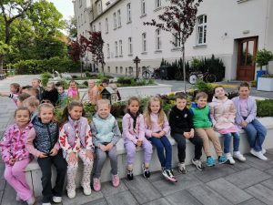 Dzieci siedzą na ławce przed szkołą