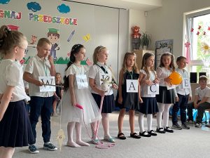 Siedmioro dzieci stoi w rzędzie trzymając atrybuty używane podczas inscenizacji