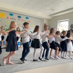 Dzieci stoją w rzędzie i tańczą
