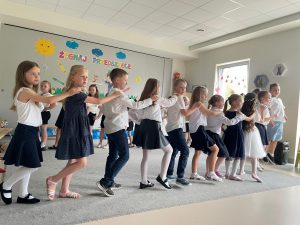 Dzieci stoją w rzędzie i tańczą
