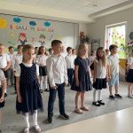 Dzieci stoją w trzech rzędach i śpiewają