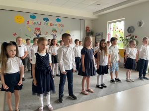 Dzieci stoją w trzech rzędach i śpiewają