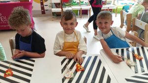 Troje chłopców i siedzi przy stole i pokazuje wykonane przez siebie lizaki