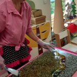 Pani stoi przy stole i przygotowuje masę do robienia lizaków