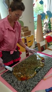 Pani stoi przy stole i przygotowuje masę do robienia lizaków