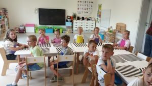 Dzieci siedzą w sali przy stołach