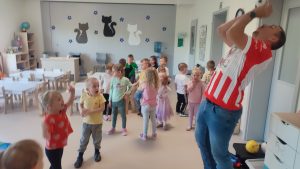 Dziecko wychodząc z tunelu rzuca piłkę do mężczyzny ubranego w koszulkę klubu Ostrovia.
