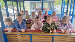 Dzieci klęczą na drewnianych ławkach w środku wagonu kolejki.
